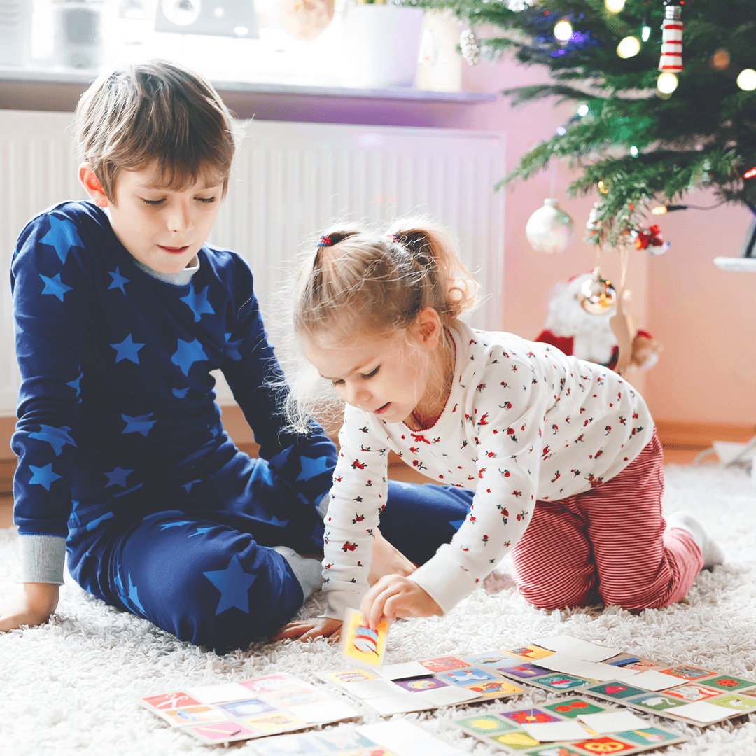 Siblings playing a board game and laughing together.