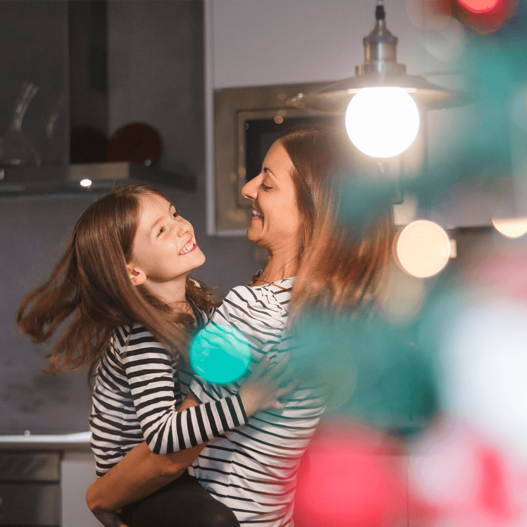 A mother and daughter dancing happily in the kitchen before Christmas.