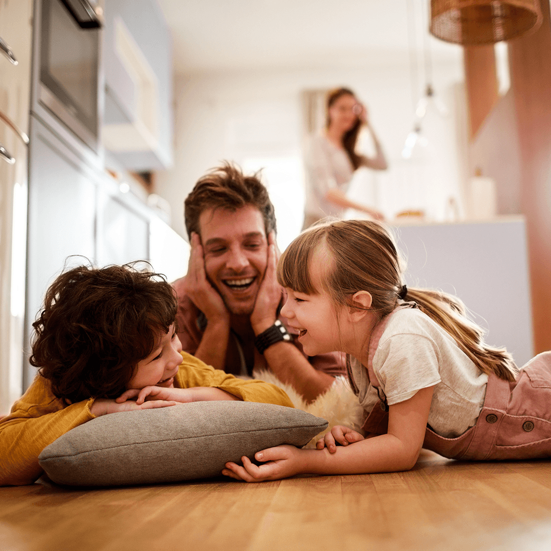Father and children lying on the floor, laughing together.