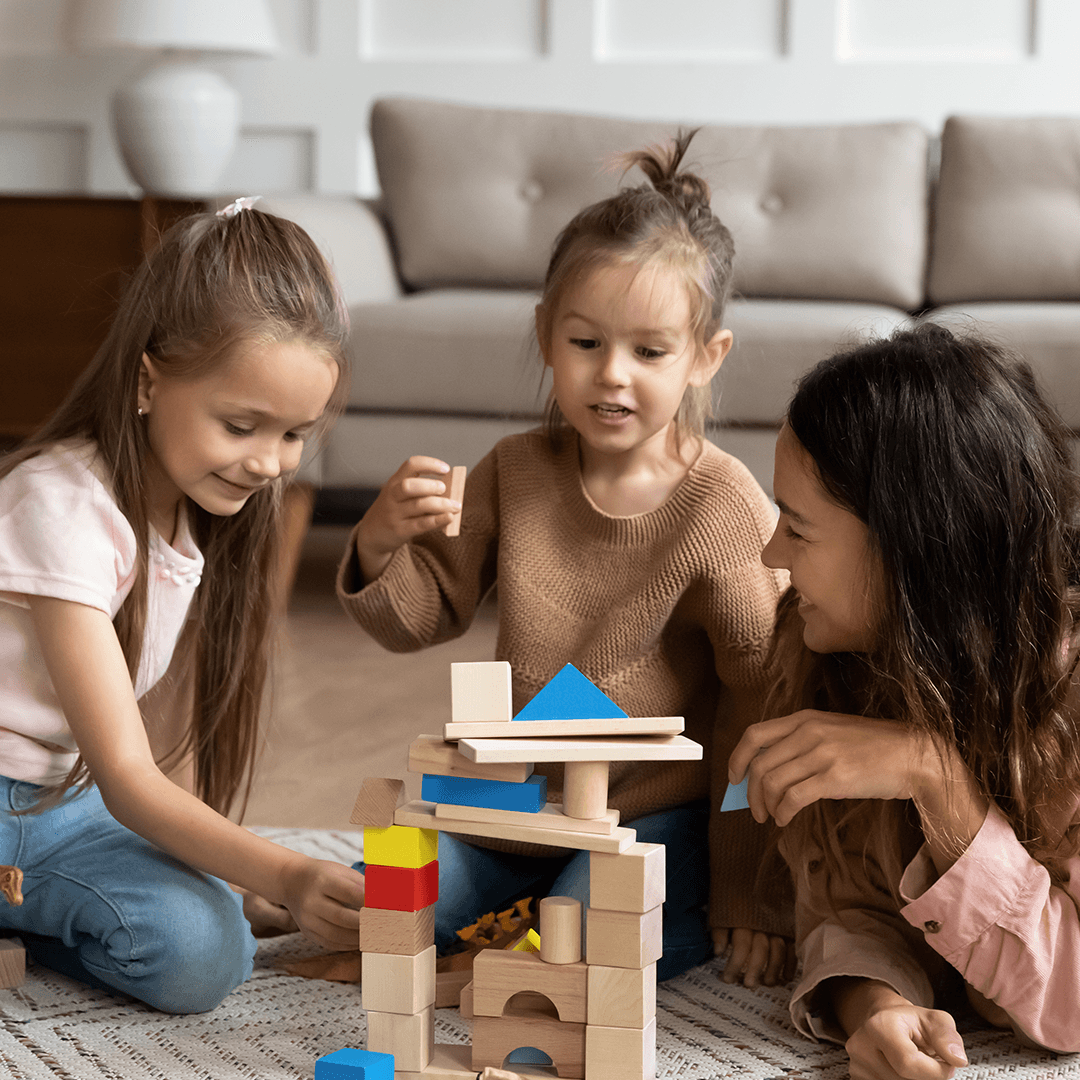 Mom and children building a tower on the floor as a winter break indoor activity
