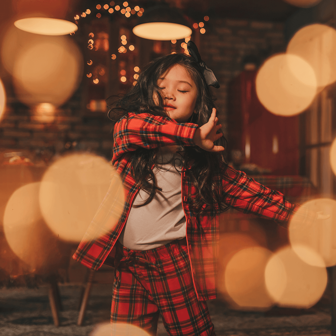 Girl dancing in pyjamas in the living room, enjoying playful holiday moments.