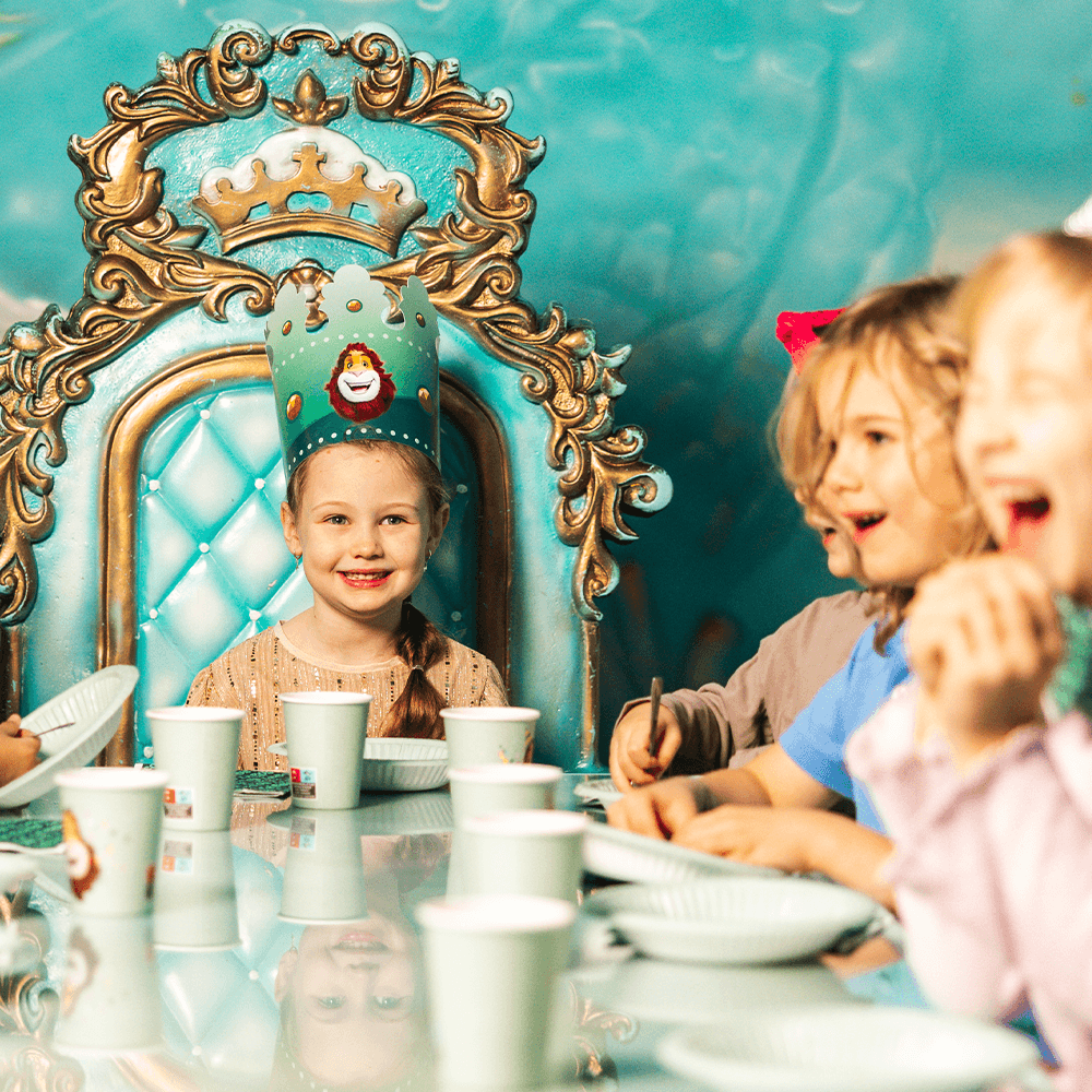 Das Geburtstagskind sitzt zufrieden am Kopfende des Tisches beim Kindergeburtstag im Leo's Abenteuerpark